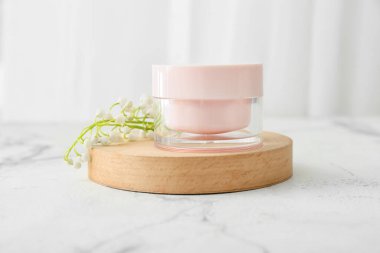 Krema kavanozu ve açık arkaplanda çiçekleri.