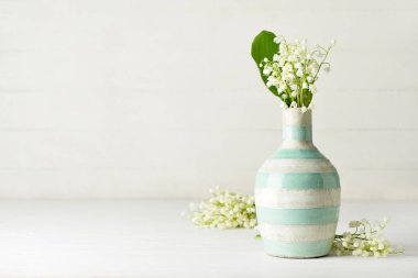 Vadideki güzel çiçekli vazo açık ahşap arka planda.