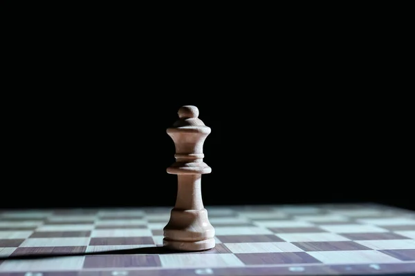 Chess board with queen on dark background, closeup