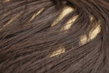 Açık arkaplanda güzel kahverengi saçlar, yakın plan.