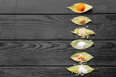 Koyu ahşap arka planda farklı tuz ve defne yapraklarına sahip kompozisyon, yakın plan.