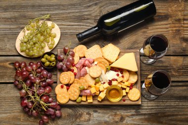 Lezzetli krakerler, peynir ve ahşap arka planda atıştırmalıklar.