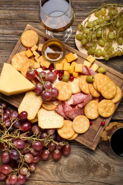 Lezzetli krakerler, peynir ve ahşap arka planda atıştırmalıklar.