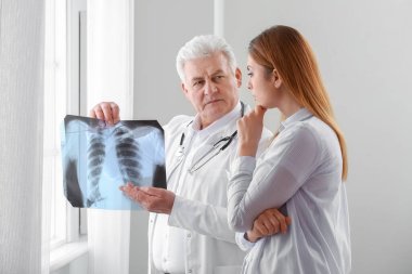 Ciğerlerinin röntgenini çeken kıdemli doktor ve klinikteki kadın hasta.