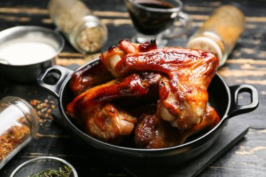 Koyu ahşap arka planda kızarmış tavuk kanatlarıyla kızartma tavası.