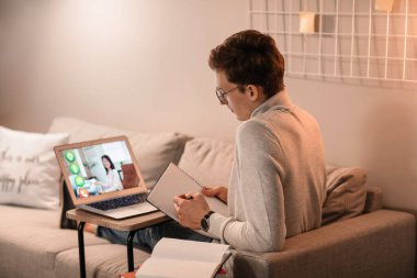 Genç adam akşam evde online çalışıyor.