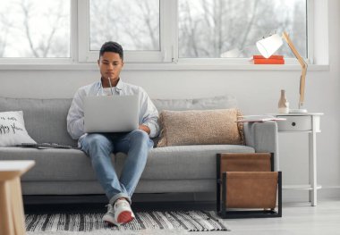 Genç Afro-Amerikalı çocuk evde online çalışıyor.