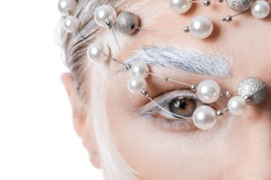 Beyaz arka planda boyalı kaşları ve şık aksesuarları olan güzel genç bir kadın.