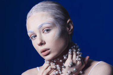 Renkli kaşları ve kolyesi olan güzel bir genç kadın.