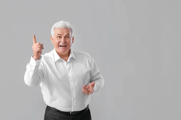 Senior Zakenman Met Opgeheven Wijsvinger Grijze Achtergrond Begrip Idee — Stockfoto