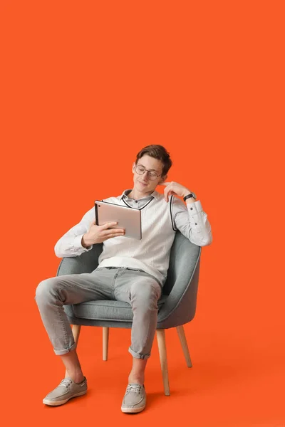 Mladý Muž Počítačem Tablet Sedí Křesle Barevném Pozadí — Stock fotografie