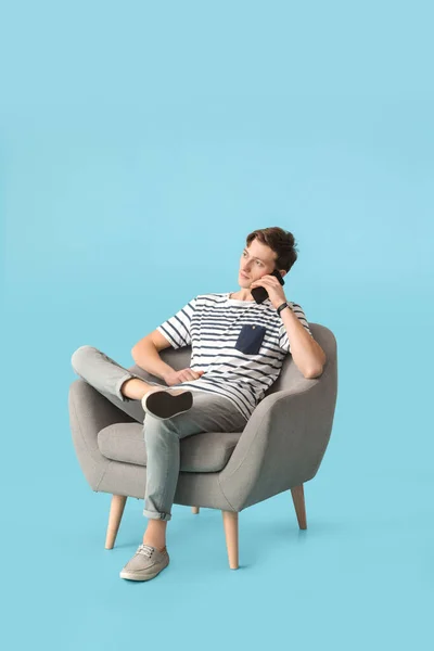 Joven Con Teléfono Sentado Sillón Sobre Fondo Color — Foto de Stock