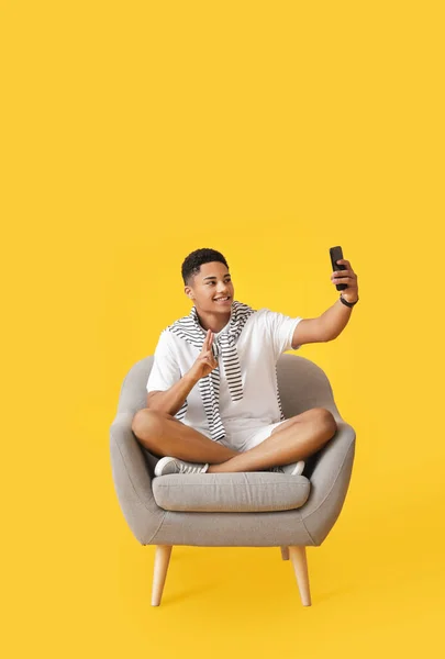 Young African American Guy Phone Sitting Armchair Color Background — Stock Photo, Image