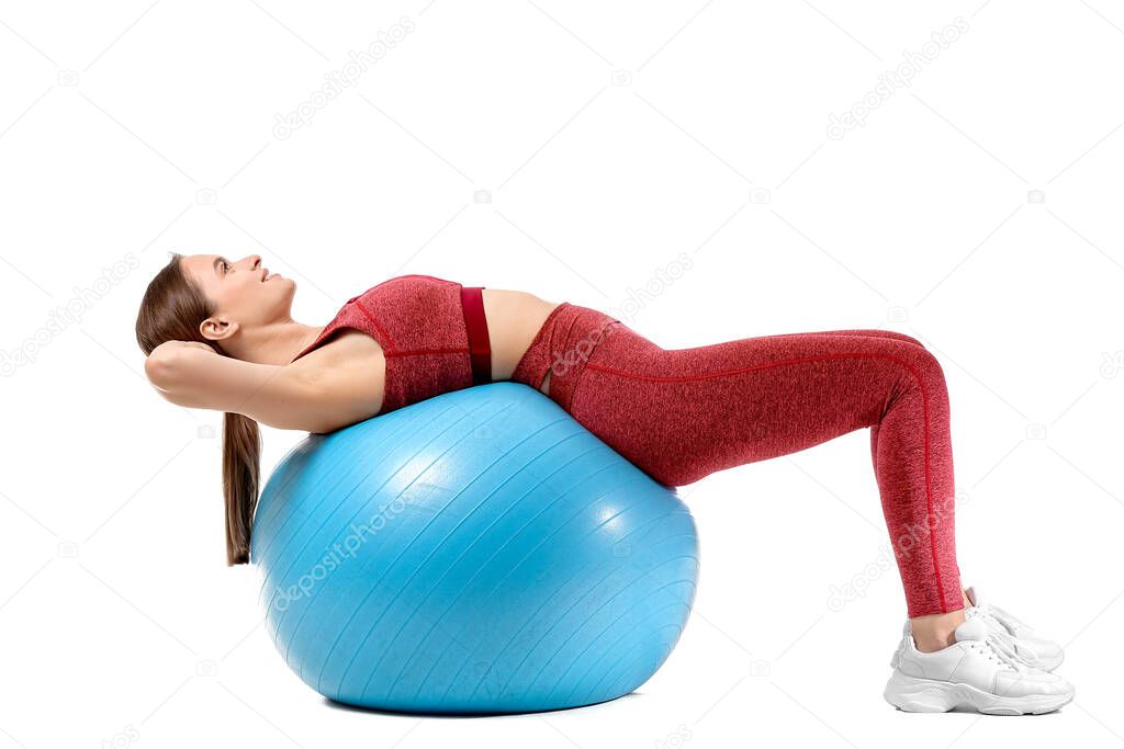 Sporty young woman training with fitball on white background