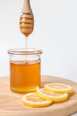 Tatlı bal, beyaz arka planda cam kavanoza damlıyor.