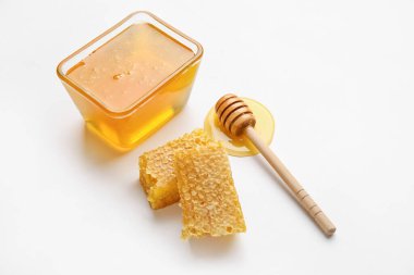 Tatlı ballı cam kase, beyaz arka planda taraklar.