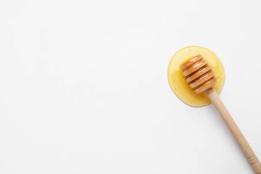 Tahta kaplama ve beyaz arka plana bal dökülmüş.