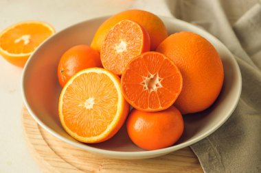 Sağlıklı portakallı tabaklar ve hafif arka planda mandalinalar.