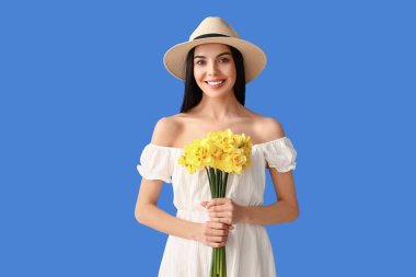 Arka planda narsis buketi olan güzel genç bir kadın.