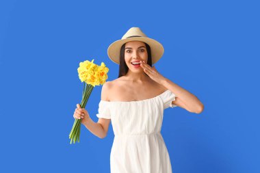 Arka planda narsis buketi olan şaşırmış genç bir kadın.