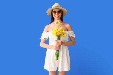 Arka planda narsis buketi olan güzel genç bir kadın.