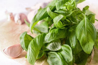 Taze fesleğen yaprakları ve arka planda sarımsak, yakın plan.