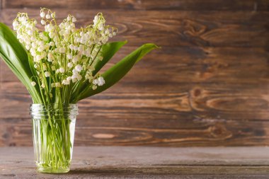 Vadideki güzel çiçekli vazo ahşap arka planda.