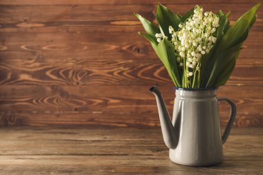 Ahşap arka planda güzel çiçekli bir çaydanlık.