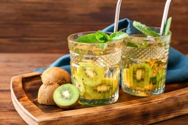 Ahşap zemin üzerinde kivi olan bir bardak lezzetli buzlu çay.