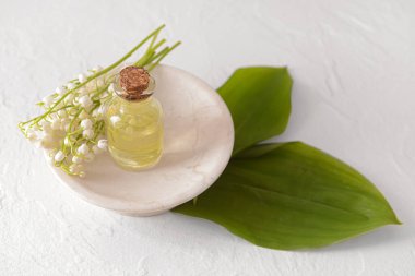 İçinde gerekli yağ ve açık arkaplanda çiçekleri olan bir şişe.