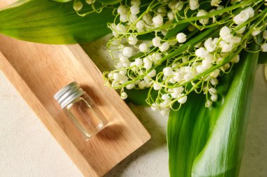 İçinde gerekli yağ ve açık arkaplanda çiçekleri olan bir şişe.