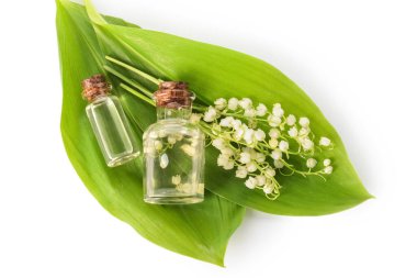 Önemli yağlı şişeler ve beyaz arka planda zambak çiçekleri.