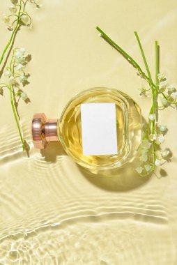 Bir şişe parfüm ve arka planda sudaki çiçekleri.