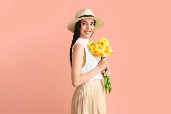 Beautiful young woman with  narcissus bouquet on color background