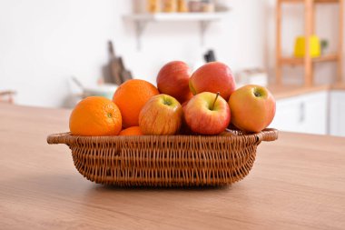 Mutfaktaki ahşap masada taze meyve dolu sepet.