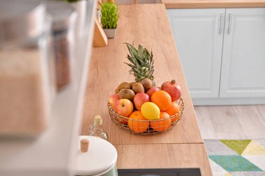 Mutfaktaki ahşap masada taze meyve dolu sepet.