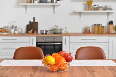 Mutfaktaki ahşap masada taze meyve dolu sepet.