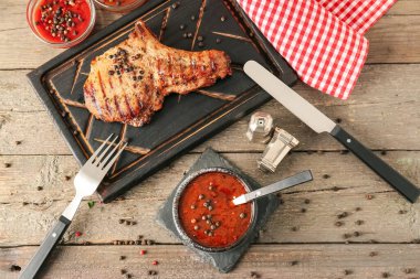 Biber soslu kase ve ahşap arka planda kızarmış et.