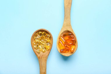 Beyaz arka planda balık yağı kapsüllü kaşıklar