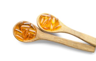 Beyaz arka planda balık yağı kapsüllü kaşıklar