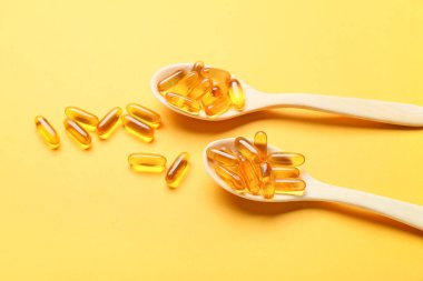 Renk arkaplanında balık yağı kapsüllü kaşıklar