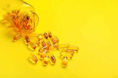 Renkli arka planda balık yağı kapsülleri olan şişe