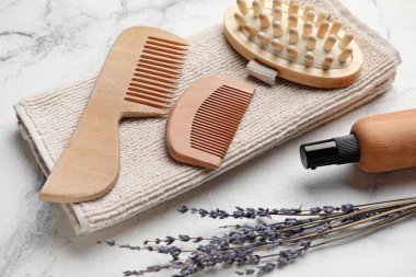 Saç tarakları, masaj fırçası, havlu ve arka planda bir şişe kozmetik ürünü.