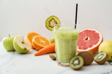 Bir bardak sağlıklı kivi püresi ve hafif arka planda malzemeler.