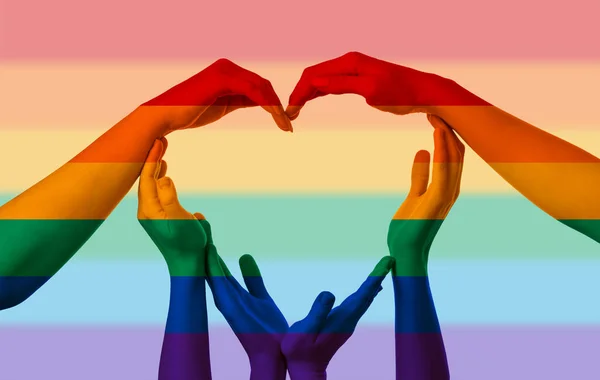 People making heart with their hands painted in colors of LGBT flag on rainbow background