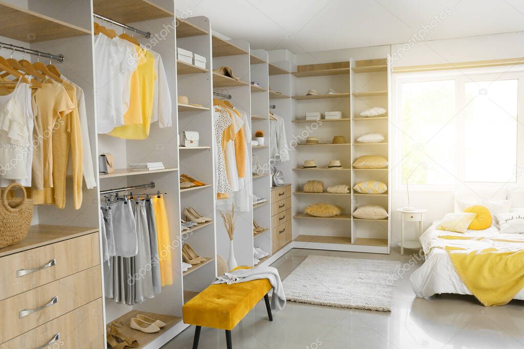 Big wardrobe with different clothes and accessories in bedroom