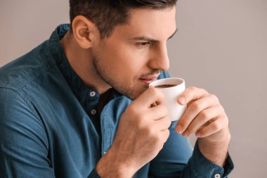 Yakışıklı genç adam arka planda kahve içiyor, yakın plan.