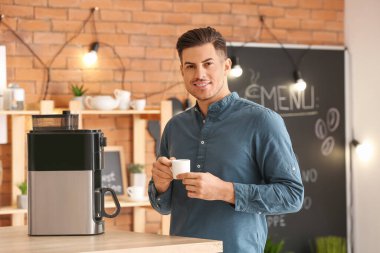 Kafede kahve içen yakışıklı genç adam.