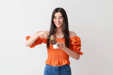 Arka planda kahve demliği ve fincanı olan güzel genç bir kadın.