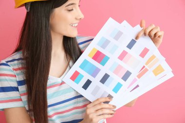 Renk arka planında palet örnekleri olan genç bir kadın.